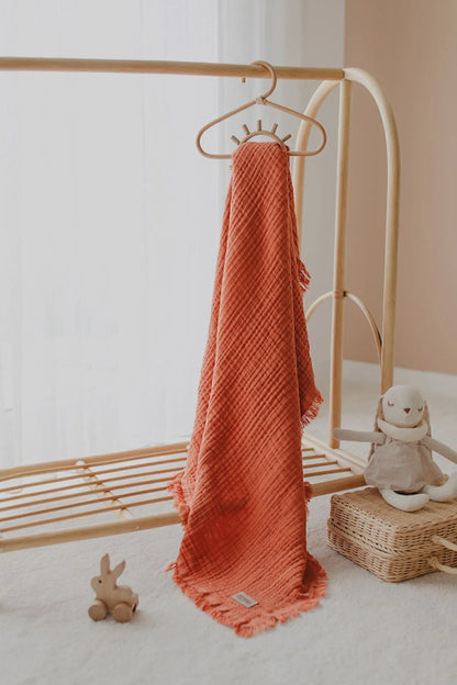 Bold and stylish brick red muslin blanket, adding a touch of color to your nursery